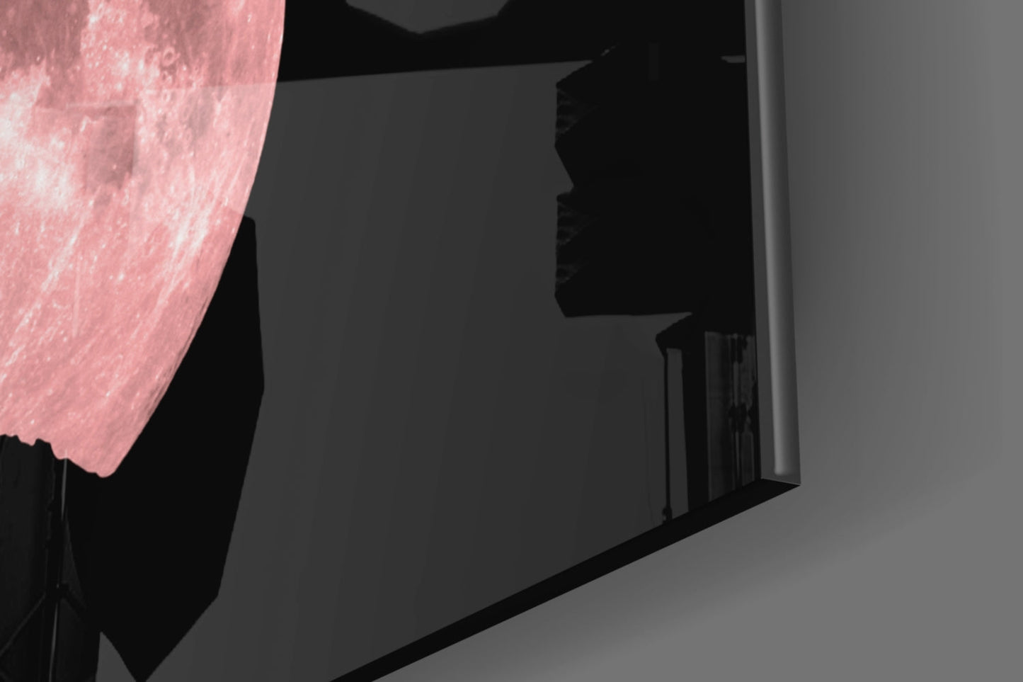 Pink fabric drape illuminates dark glass wall art panel mounted on gray wall interior.