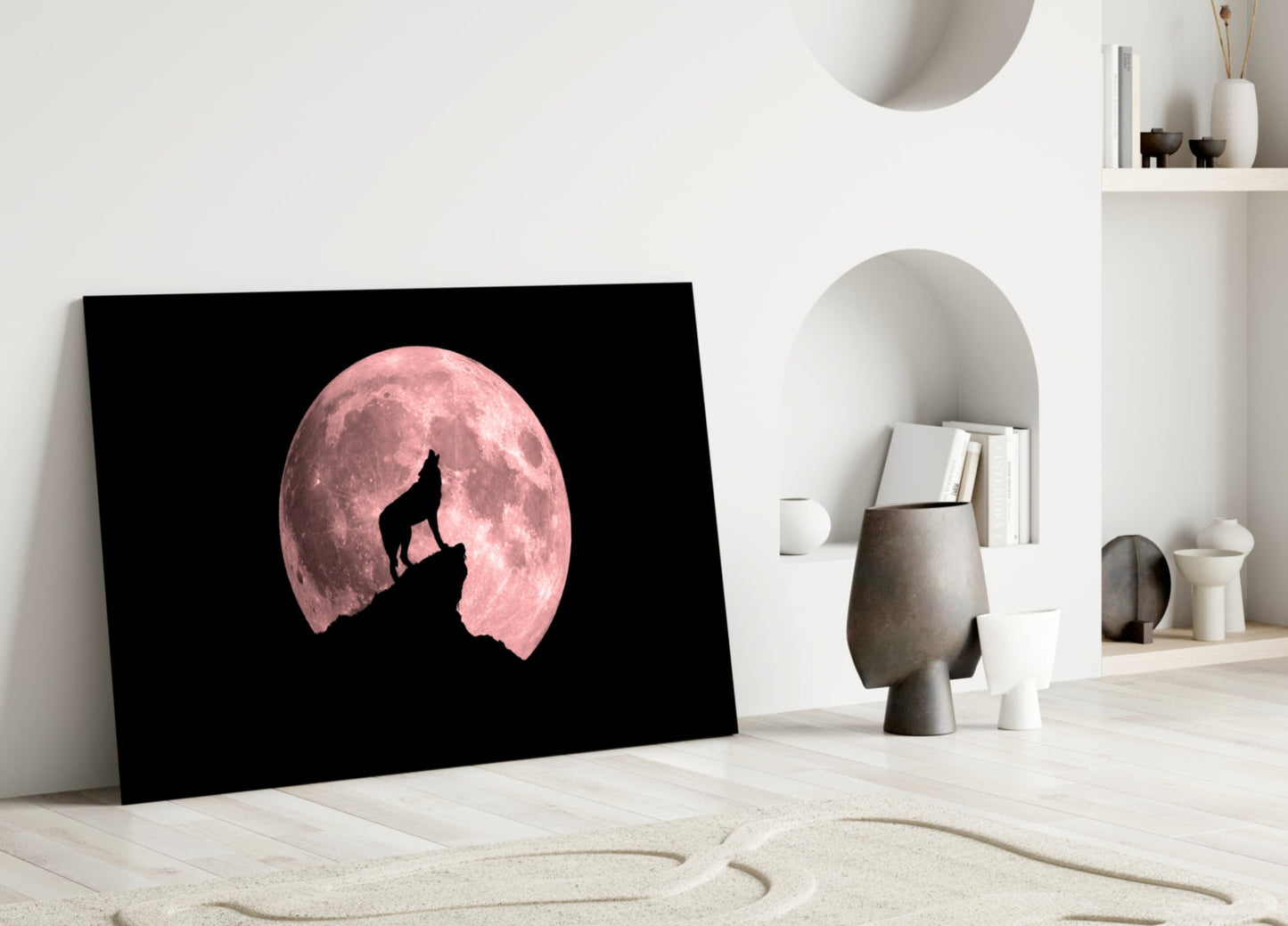 Black glass wall art featuring a silhouetted wolf howling at a pink full moon, displayed in a minimalist white interior space.