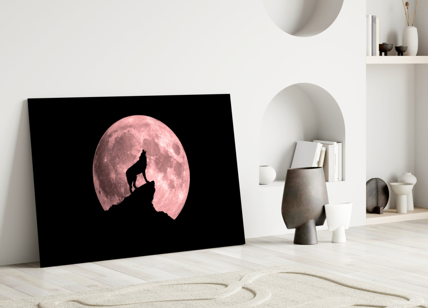 Black glass wall art featuring a silhouetted wolf howling at a pink full moon, displayed in a minimalist white interior space.