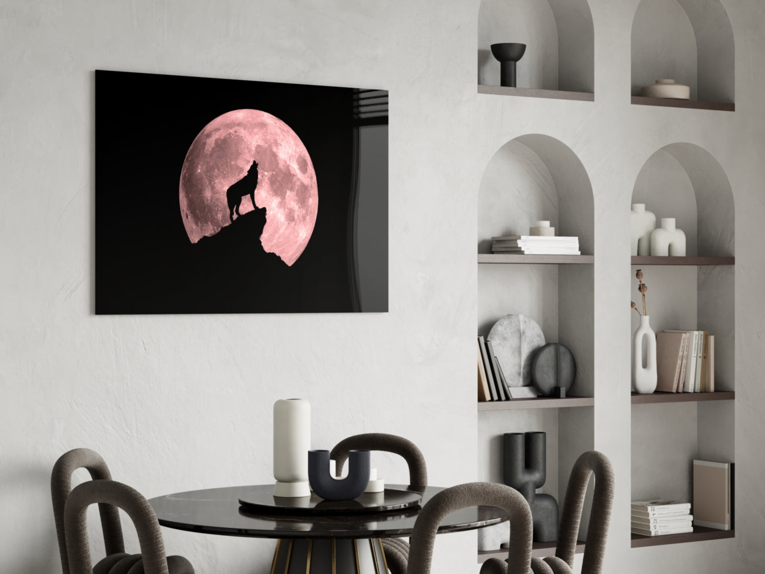 Wolf and full moon glass wall art displayed above a black dining table in a minimalist room with built-in shelving.