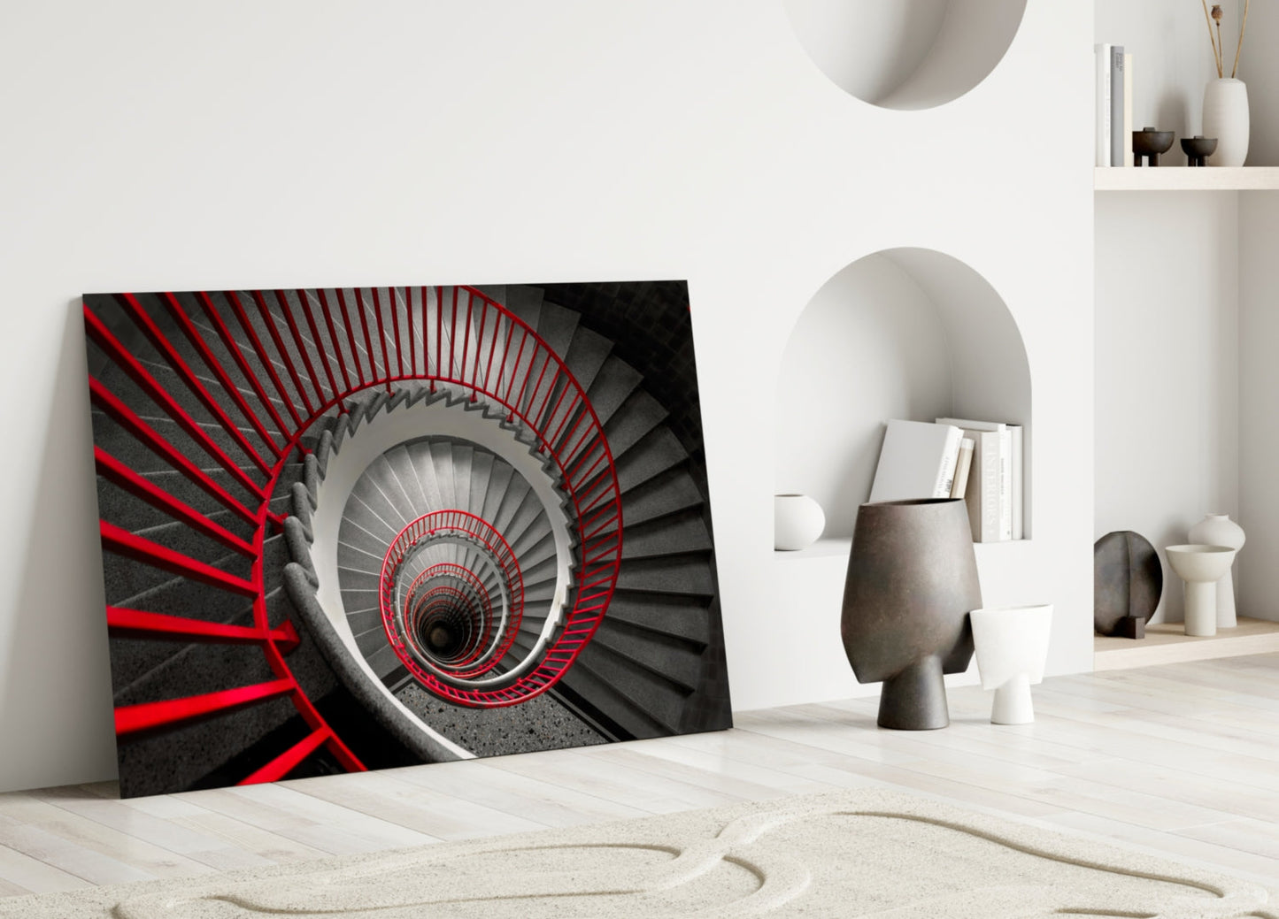 Red and black spiral staircase glass wall art leaning against white wall in minimalist interior setting.