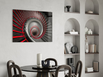 Red and gray spiral staircase glass wall art displayed above black round dining table in modern interior with built-in shelving.