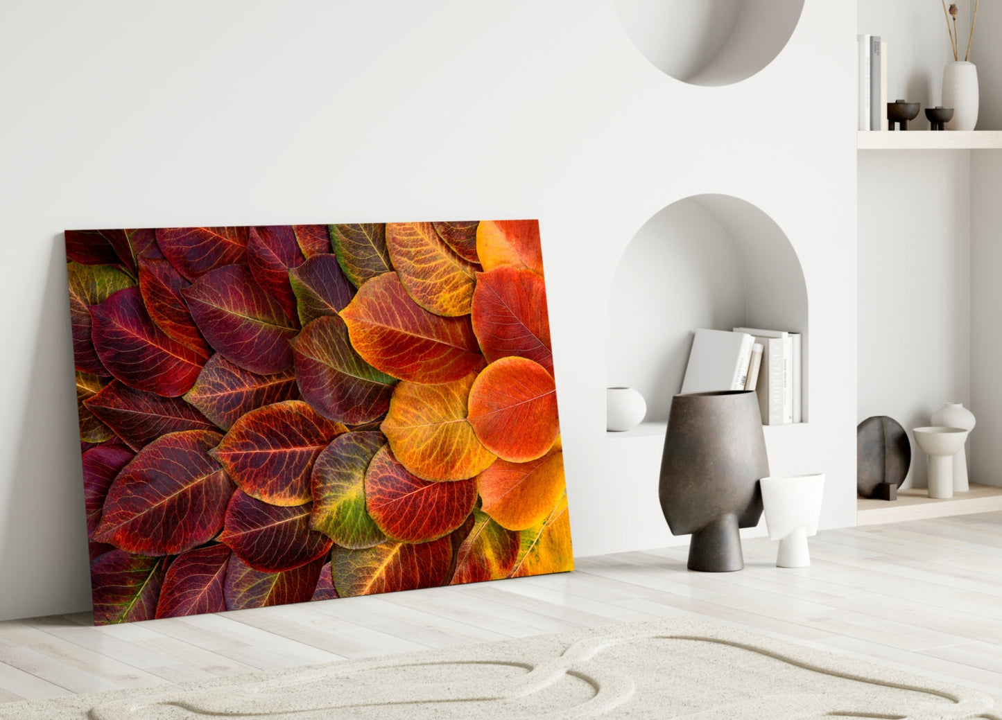 Vibrant autumn leaves glass art leaning against white wall in minimalist interior setting with decorative objects.