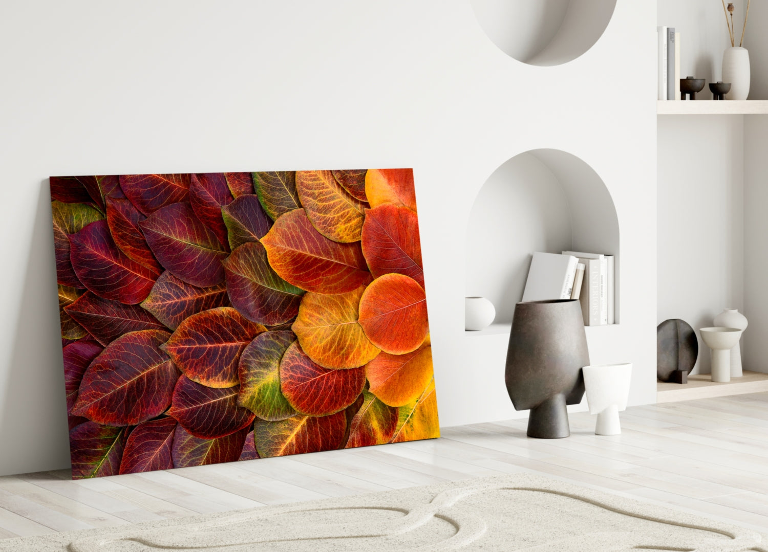 Vibrant autumn leaves glass art leaning against white wall in minimalist interior setting with decorative objects.