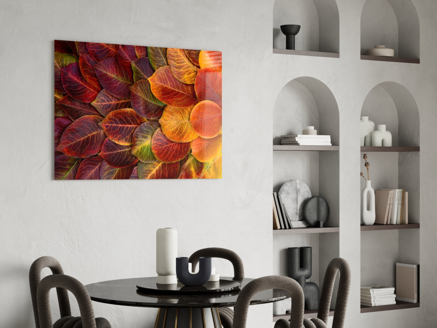 Orange Leaves Glass Wall Art displaying vibrant red, orange, and yellow autumn foliage, hung above a round black dining table with gray upholstered chairs.
