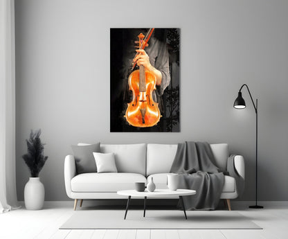 Violin glass wall art displaying a golden-brown violin held by hands against a black background, mounted above a white sofa in a modern living room setting.