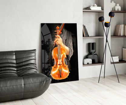 Modern living room interior featuring a leaning glass wall art depicting a glowing amber violin held by hands against black background.
