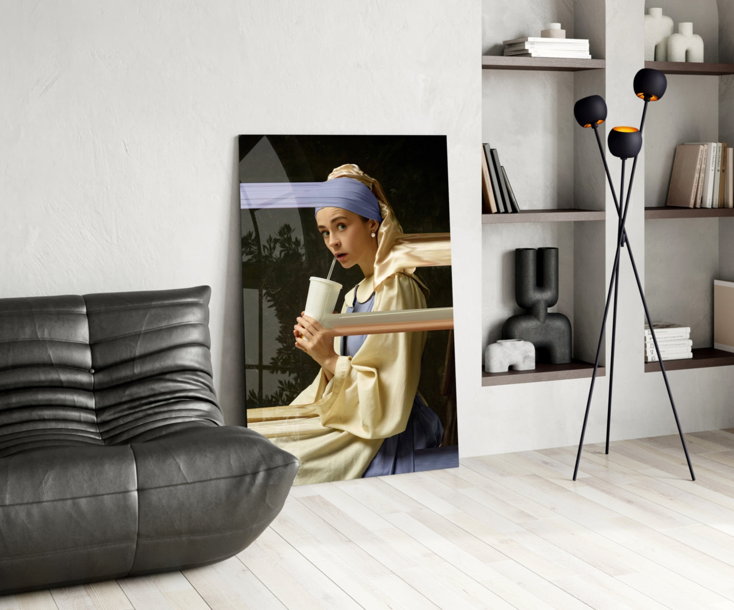 Girl with a Pearl Earring glass wall art displayed in a modern living room beside a black leather chair and shelving unit.