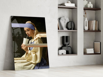 Girl with a Pearl Earring glass wall art leaning against white wall beside wooden shelving displaying books and decorative objects.
