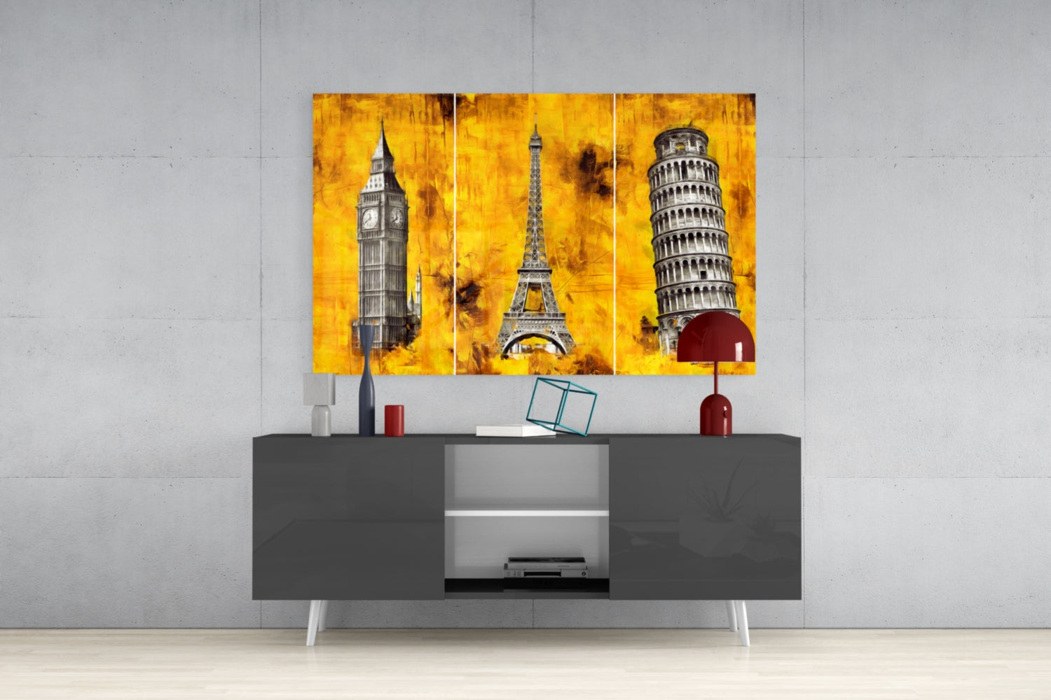 Three-panel yellow glass wall art depicting Big Ben, Eiffel Tower, and Leaning Tower of Pisa displayed above gray media console in modern interior.