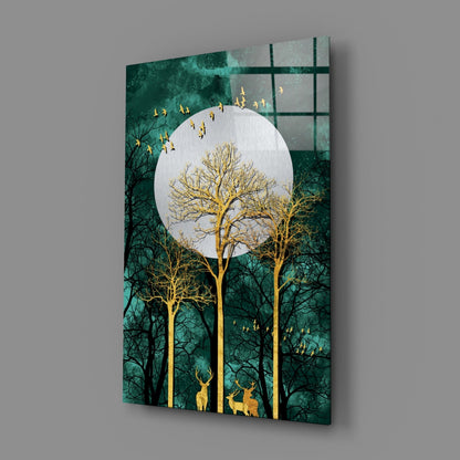 Angled view of glass wall art showing golden trees and deer beneath a white moon against a teal-green forest background.