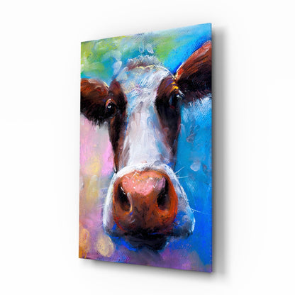 Colorful glass wall art depicting a cow's face with brown and white markings against a vibrant blue, pink, and green painted background.