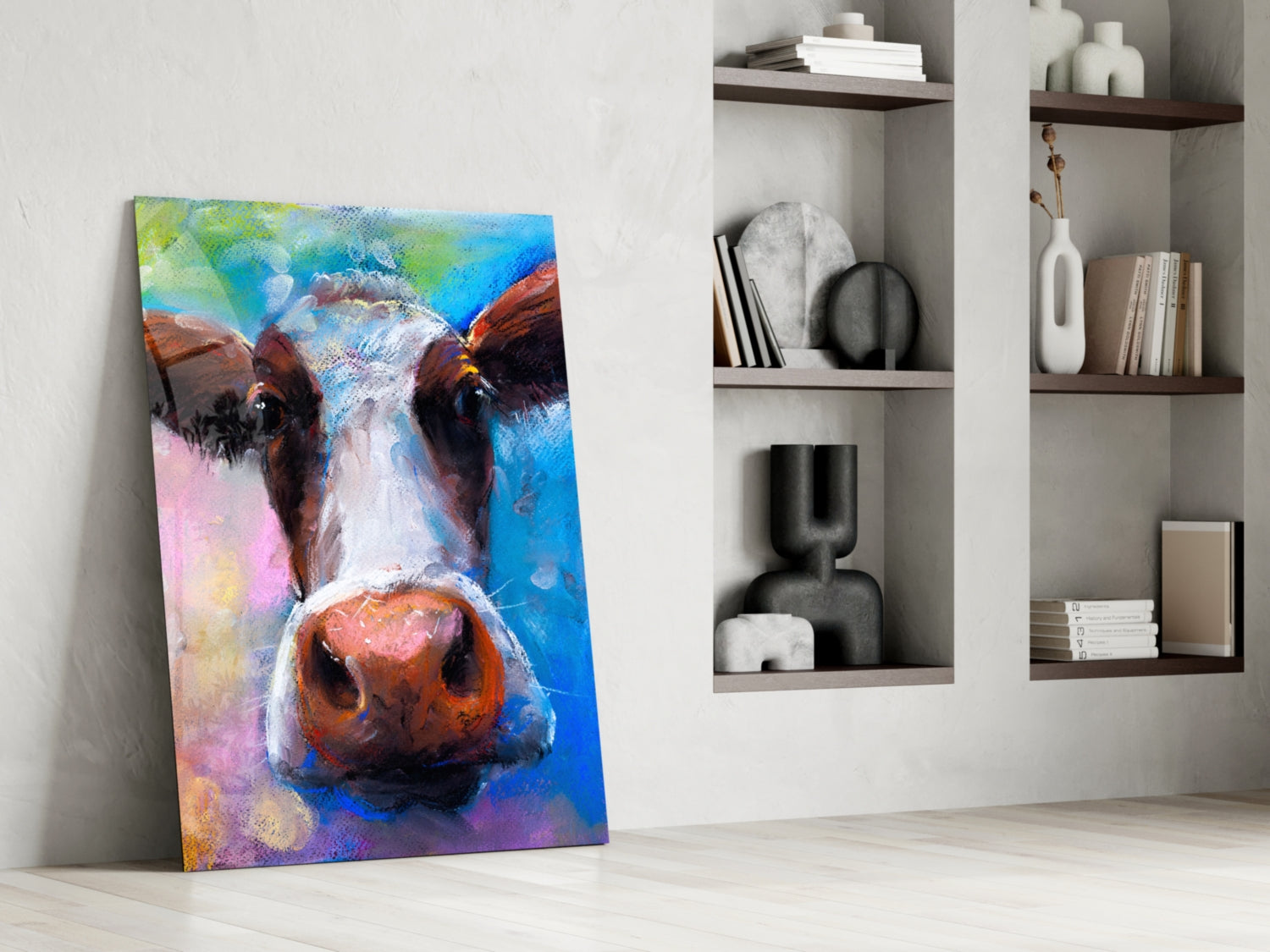 Colorful abstract cow portrait glass art leaning against white wall beside built-in shelving with decorative objects.