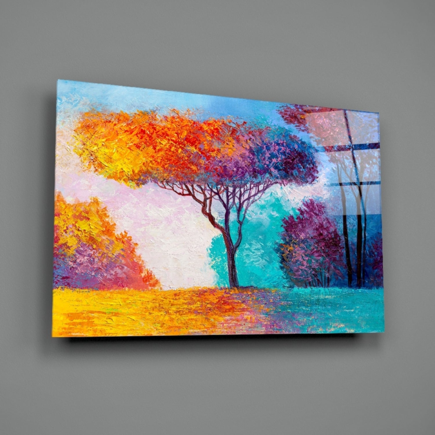 Colorful glass wall art depicting a vibrant autumn landscape with yellow, orange, and purple trees against a turquoise and blue sky, displayed at an angle against a gray wall.