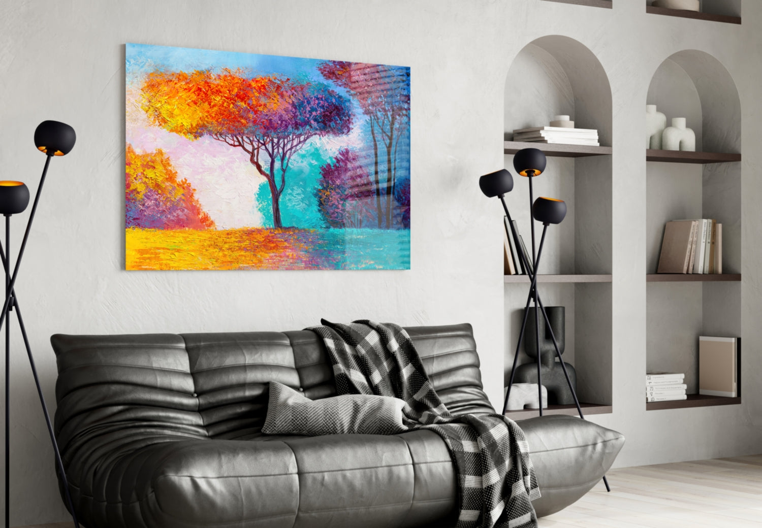 Colorful glass wall art depicting autumn trees in yellow, orange, and purple hues displayed above a black leather sofa in a modern living room.