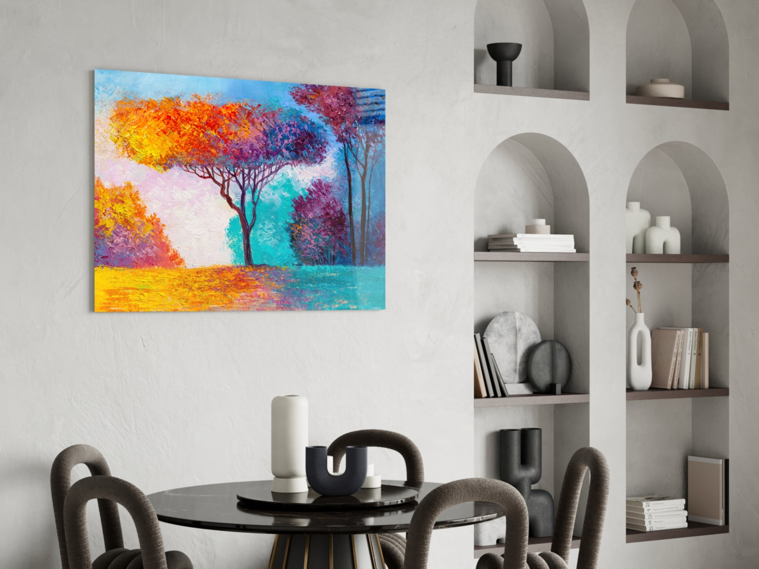 Colorful abstract tree painting with yellow, orange, purple and turquoise tones displayed above a round black table in a modern interior setting.