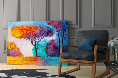 Colorful glass wall art depicting vibrant trees with yellow, orange, and purple foliage against a turquoise and blue sky, displayed in a modern interior beside a wooden rocking chair.