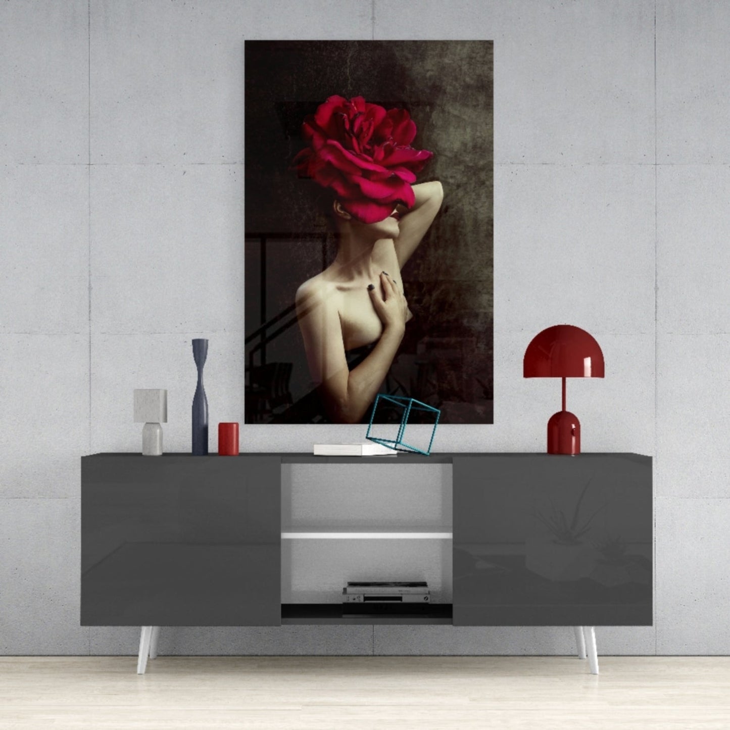 Modern living room display featuring gray media console with red lamp and decorative items beneath surreal artwork of woman with large crimson rose head.