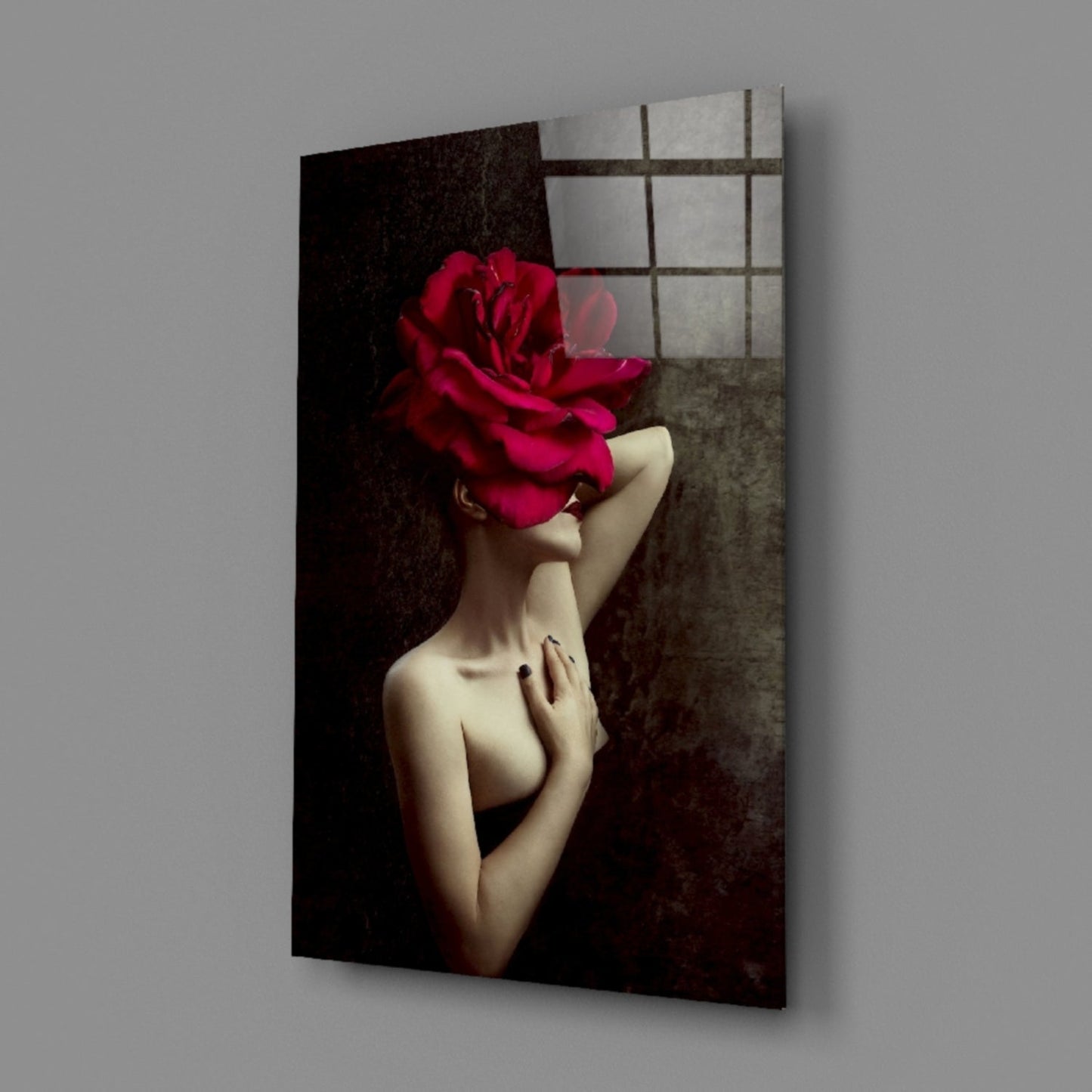 Angled view of glass wall art depicting a pale-skinned figure with arms crossed, face obscured by a large crimson rose, against dark textured background.