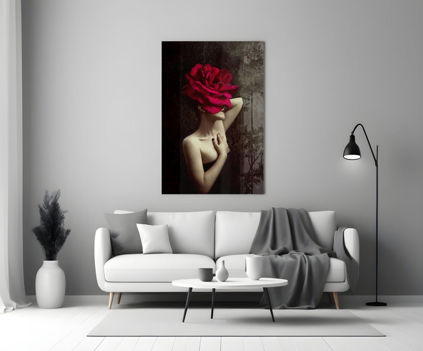 Glass wall art depicting a pale-skinned figure with a large crimson rose obscuring their face, displayed above a white sofa in a modern interior.