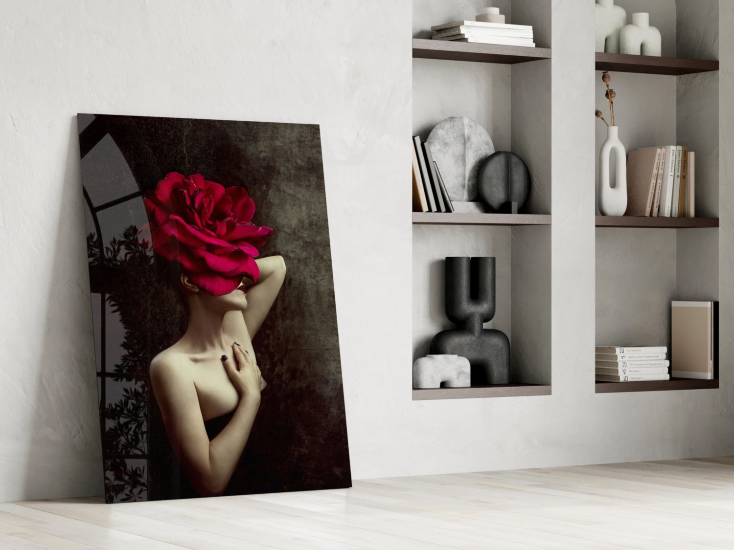 Glass wall art leaning against white wall displays woman with red rose covering face, styled shelving with books and décor visible behind.