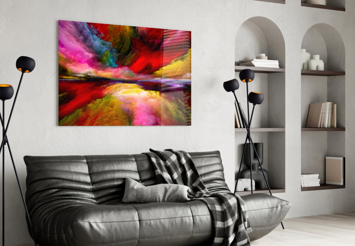 Colorful abstract glass wall art with vibrant pink, red, yellow, and blue streaks displayed above a black leather sofa in a modern living room.