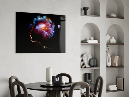 Glass wall art featuring neon orange profile silhouette with vibrant blue, purple, and orange cosmic burst, displayed above dining table in modern interior.