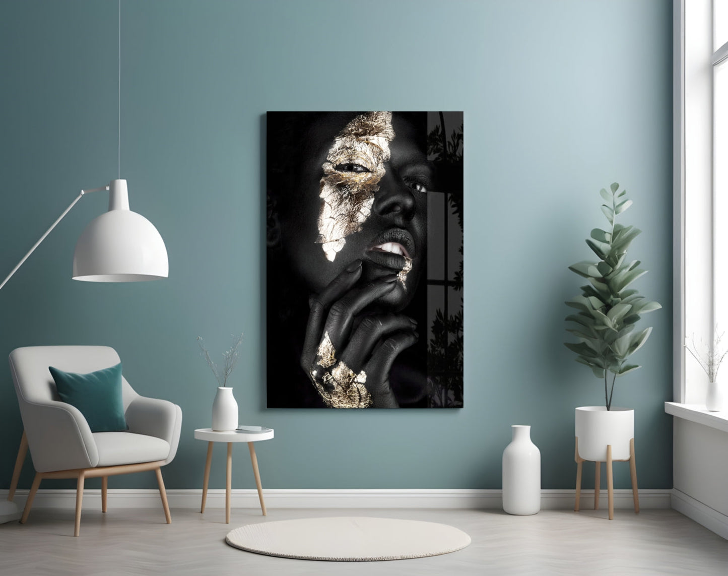 Modern interior room with turquoise walls displaying black and gold portrait glass art above cream armchair and potted plant.