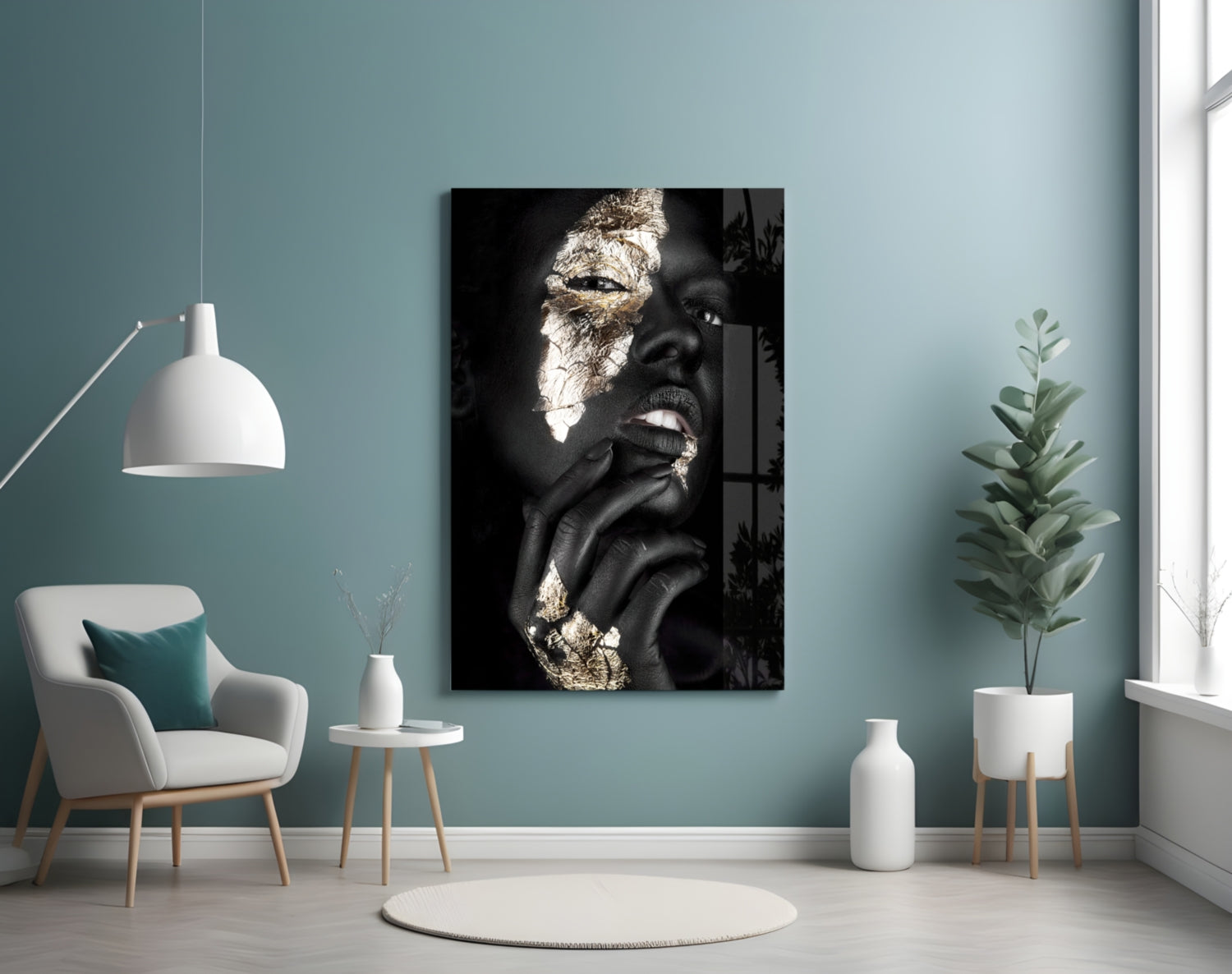 Modern interior room with turquoise walls displaying black and gold portrait glass art above cream armchair and potted plant.
