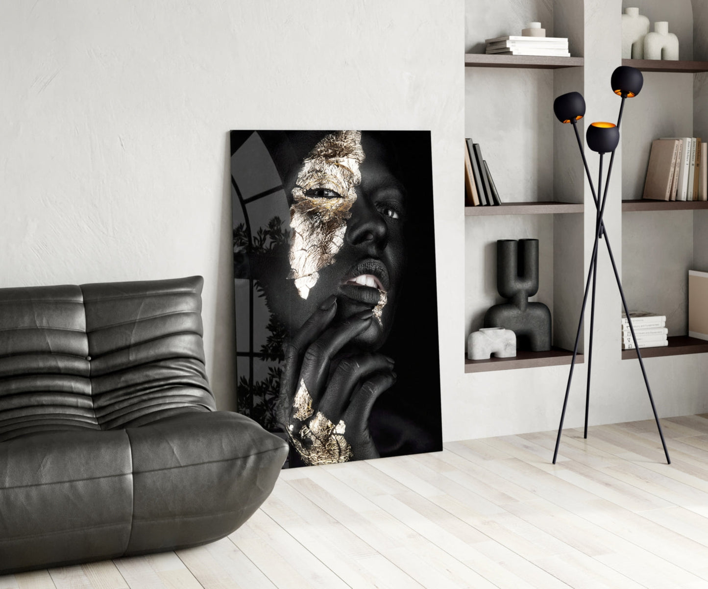 Black and gold glass wall art depicting a woman's face in profile displayed in a modern living room setting.