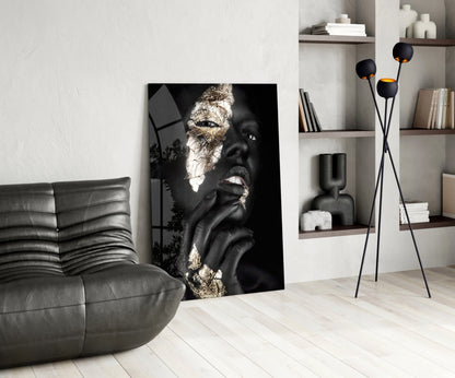 Black and gold glass wall art depicting a woman's face in profile displayed in a modern living room setting.