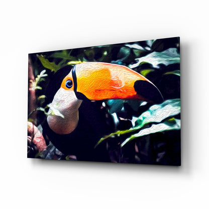 Toco toucan glass wall art displayed at an angle, showing vibrant orange and yellow beak with white and black plumage against a dark foliage background.