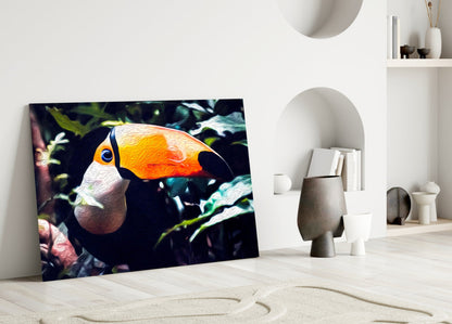 Toco Toucan glass wall art leaning against white wall in minimalist room with sand floor and decorative objects.