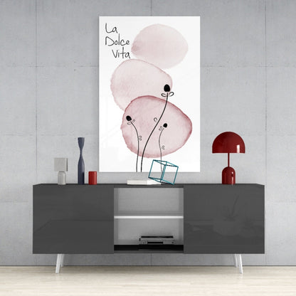 La Dolce Vita glass wall art featuring pink watercolor circles with black botanical stems, displayed above a gray console table with red accents.