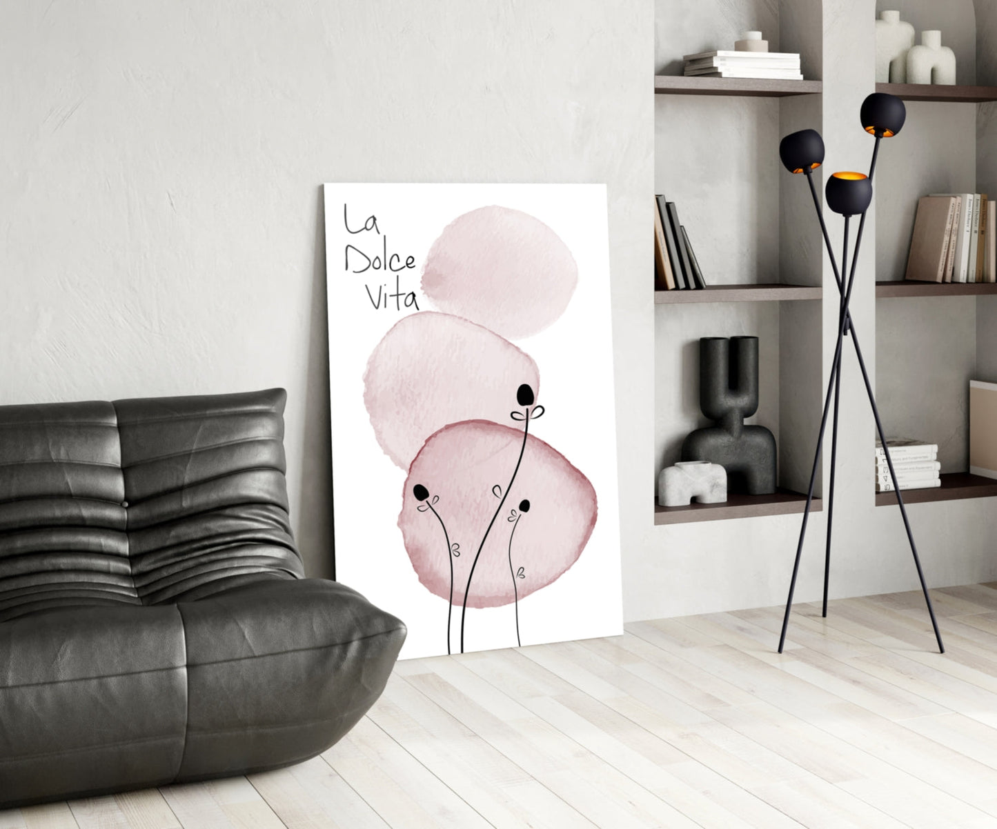 La Dolce Vita glass wall art leaning against white wall in modern living room with black leather sofa and shelving unit.