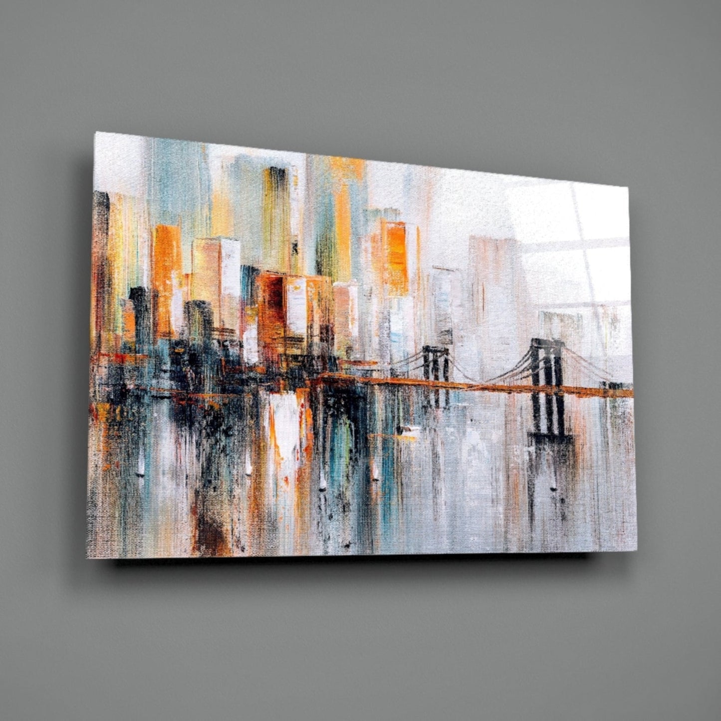 Abstract cityscape with suspension bridge, skyscrapers in warm orange and cool blue tones on textured glass panel against gray wall.