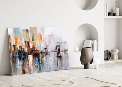 Abstract cityscape glass wall art featuring orange, blue, and gray vertical streaks with a bridge motif, displayed on white wall.