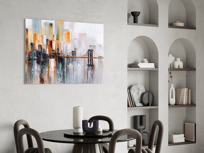 Abstract cityscape glass wall art featuring orange, blue, and white tones with bridge motif, displayed above black dining table in modern interior.