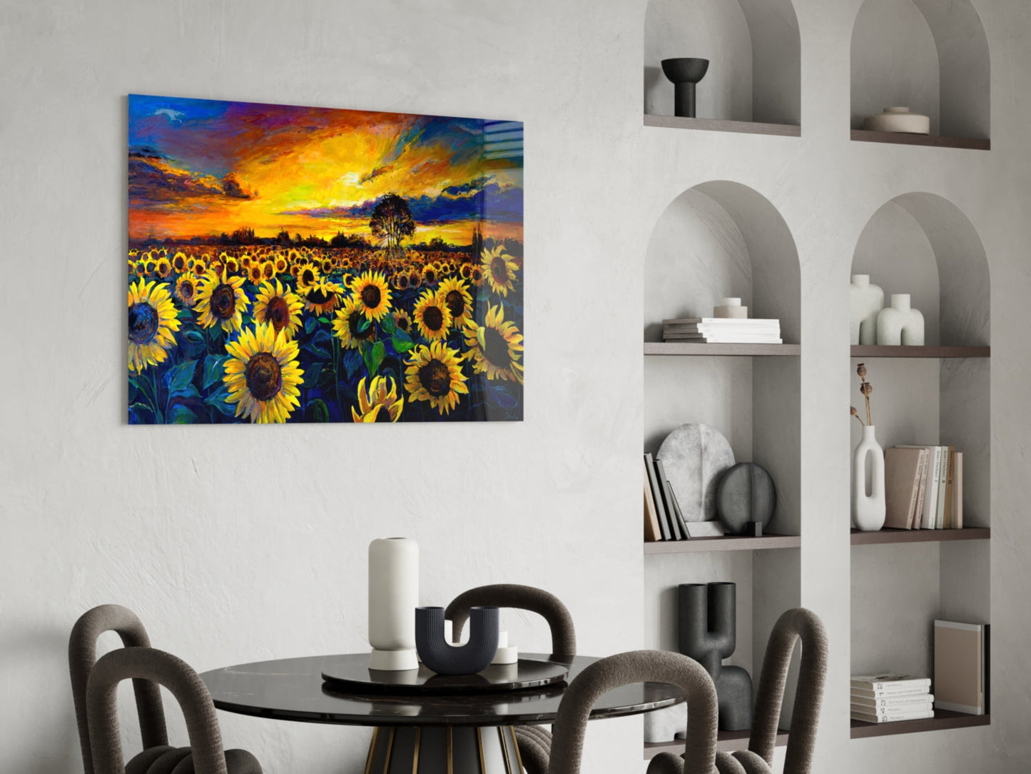 Colorful sunflower field glass art hanging above a round black dining table with gray chairs and white shelving.