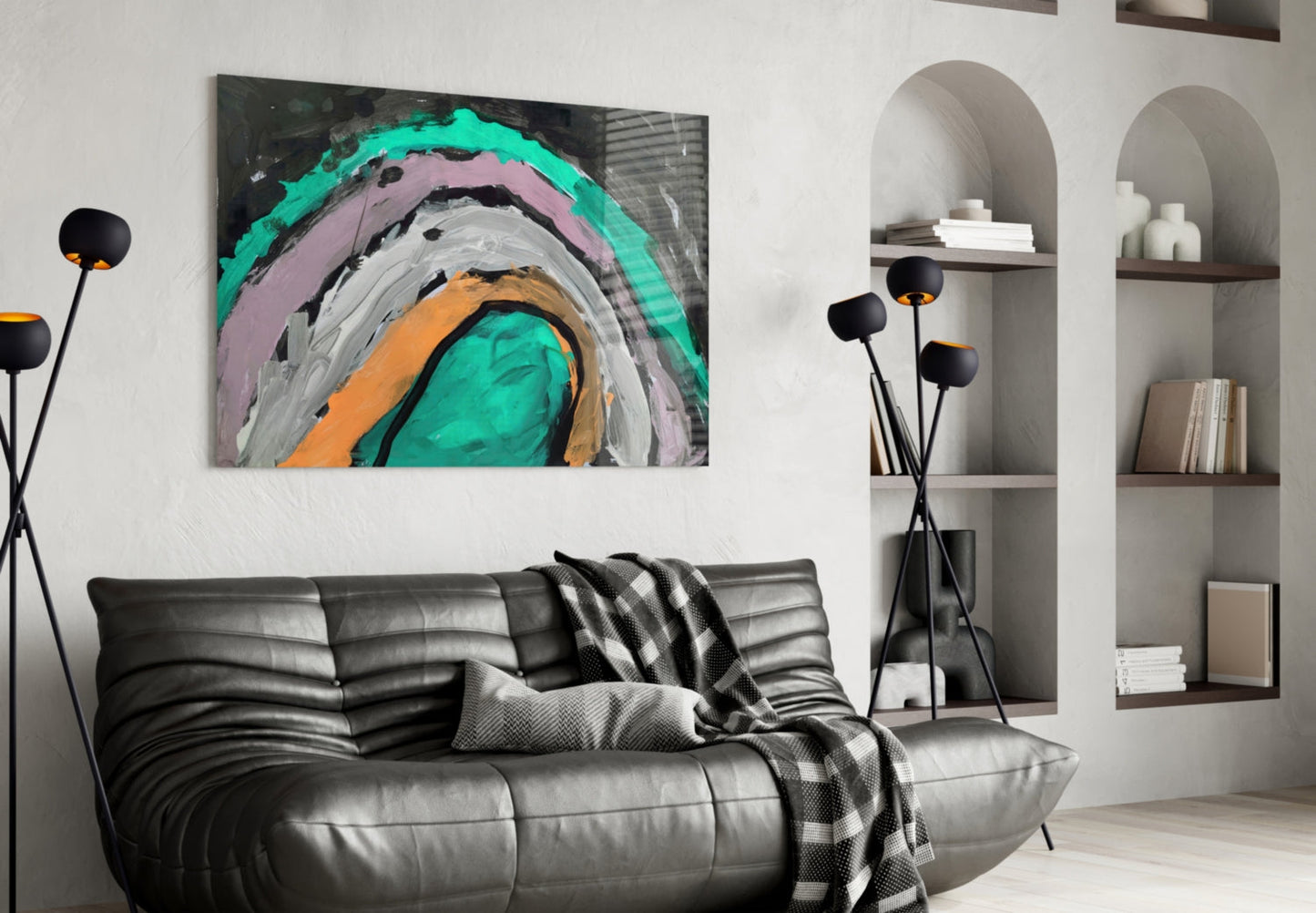 Modern living room with abstract concentric circles glass wall art in turquoise, pink, orange, and gray above black leather sofa.