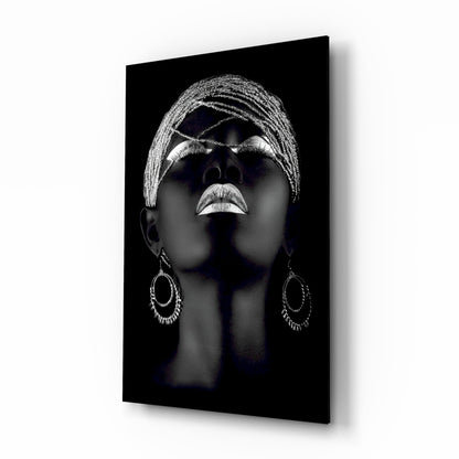 Black glass wall art featuring a silver-highlighted portrait of a woman's face tilted upward, wearing ornate hoop earrings and braided head wrap.
