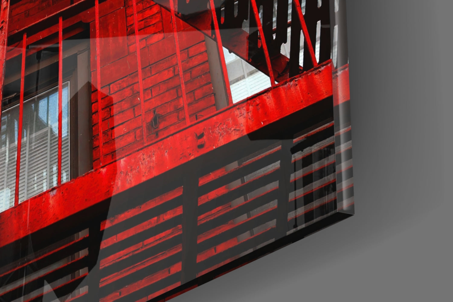 Red metal industrial staircase and railings with black horizontal slats against gray background, architectural detail view.