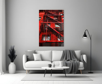 Red brick building facade with black metal fire escapes displayed as glass wall art above white sofa.