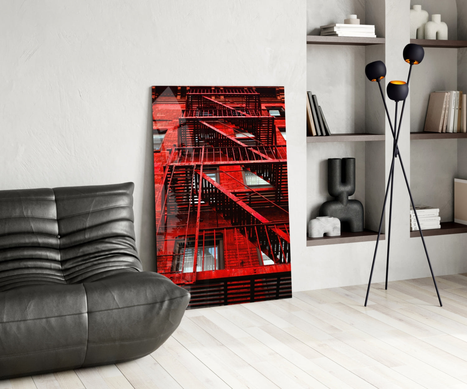 Red fire escape stairs glass wall art displayed in modern living room with gray leather chair and black floor lamp.