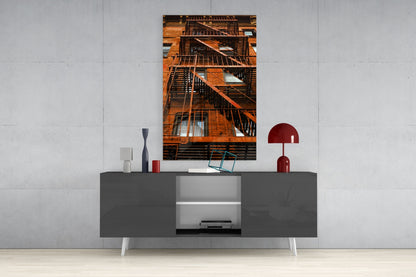 Orange brick building with black fire escape stairs and windows displayed as framed wall art above modern gray media console.