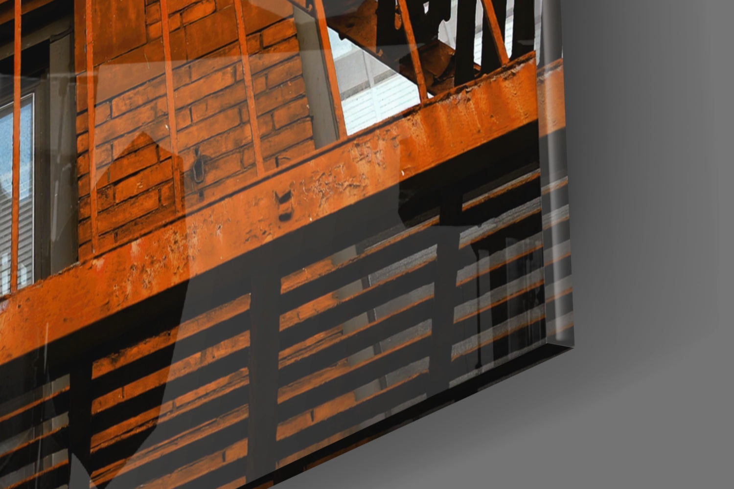 Close-up angled view of orange metal staircase with glass wall panel showing rust and weathering details.