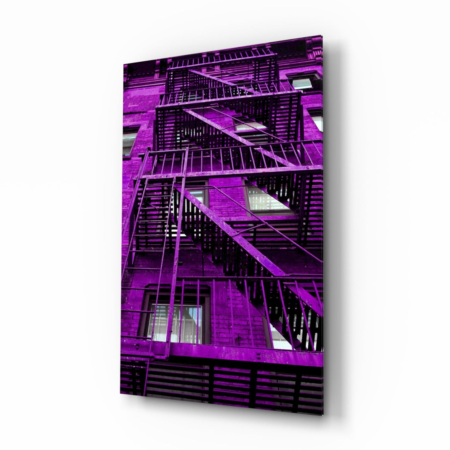 Vibrant magenta brick building facade with black metal fire escapes and windows displayed on glass wall art panel.