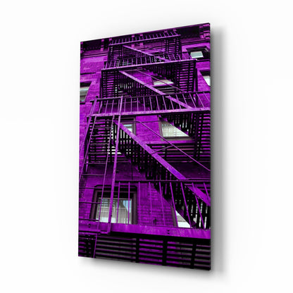 Vibrant magenta brick building facade with black metal fire escapes and windows displayed on glass wall art panel.