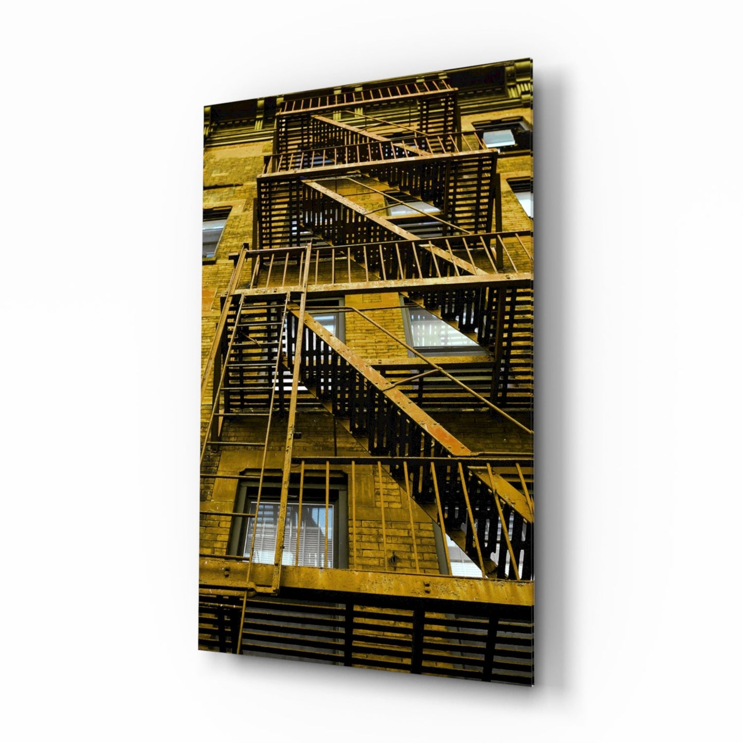 Exterior view of a brick building facade with multiple black metal fire escapes zigzagging down the yellow brick wall.