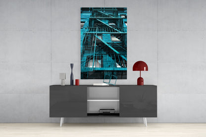 Blue-toned metal fire escape stairs displayed as vertical wall art above a dark gray media console in a modern interior setting.